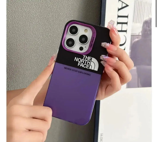 Hand holding purple and black iPhone case with The North Face logo, stylish nails visible