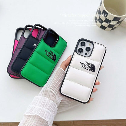 Assorted The North Face puffer phone cases in white, green, black, and pink on white table