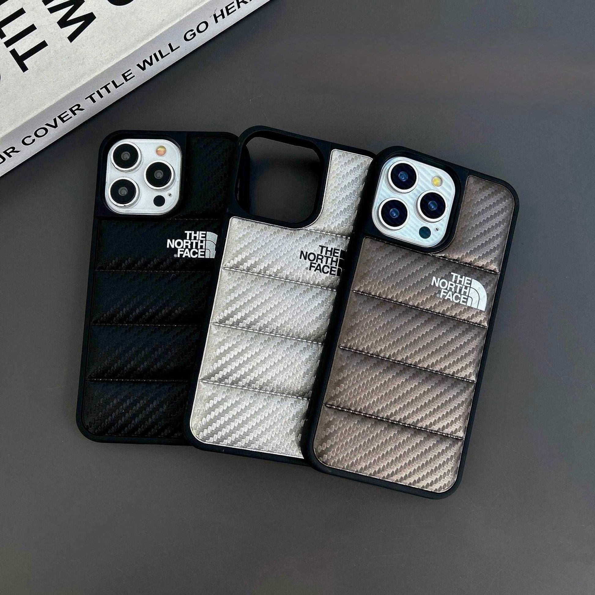 Three The North Face iPhone cases with padded, carbon fiber texture in black, silver, and brown