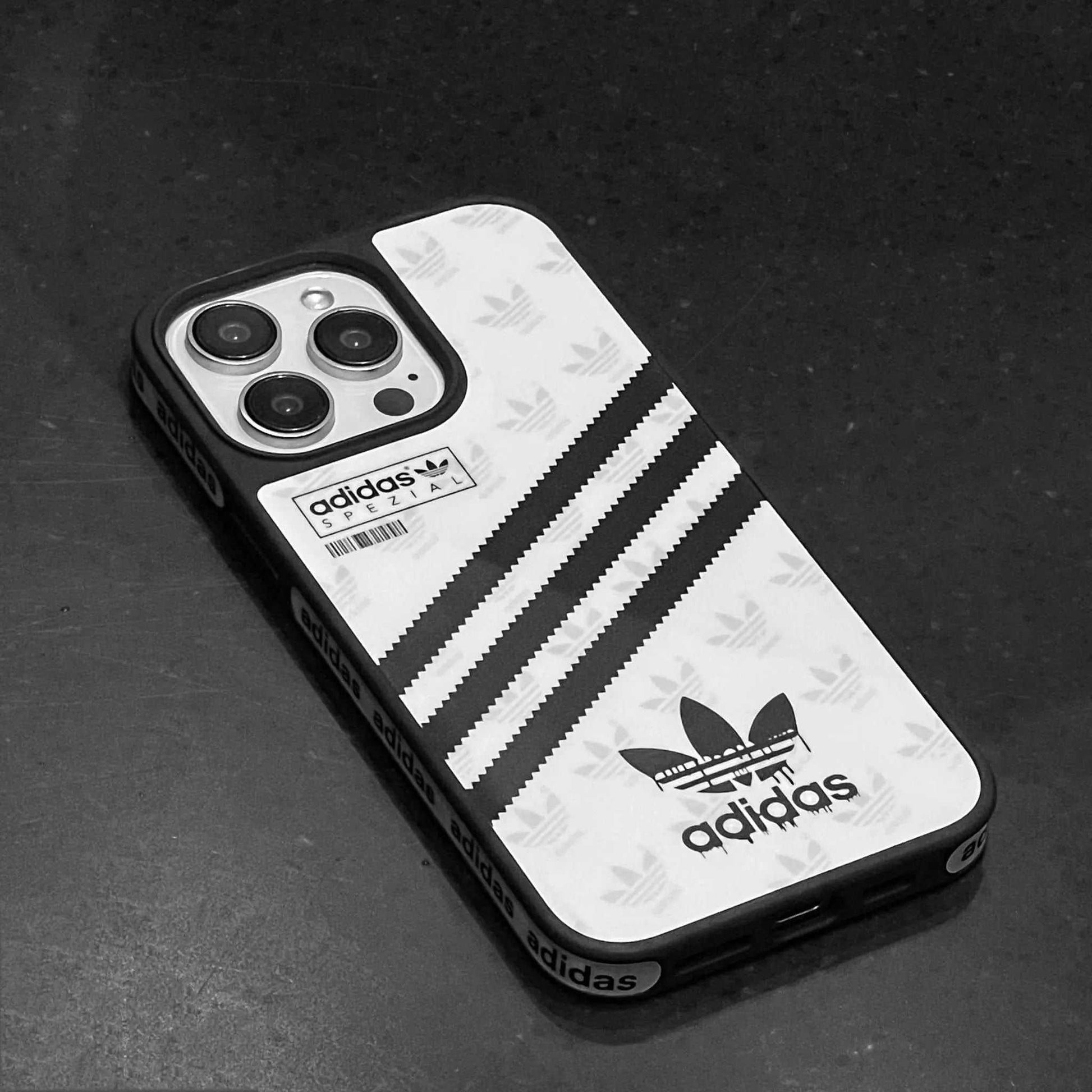 Adidas iPhone case with black stripes and logo on a dark surface