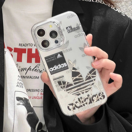 Hand holding iPhone with clear Adidas sports case featuring silver Trefoil logo and branding.