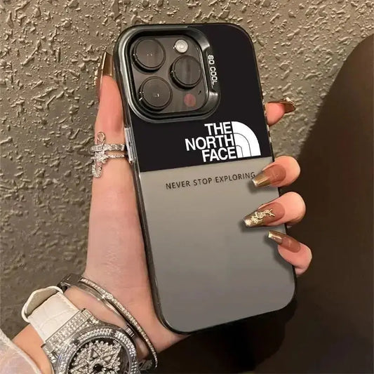 Hand holding iPhone with The North Face logo gradient case, luxury accessories visible
