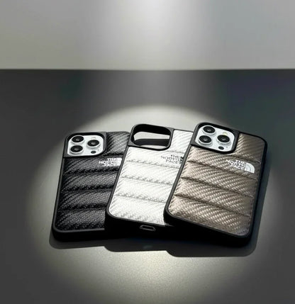 Three The North Face iPhone cases in black, white, and brown on a sleek gray surface