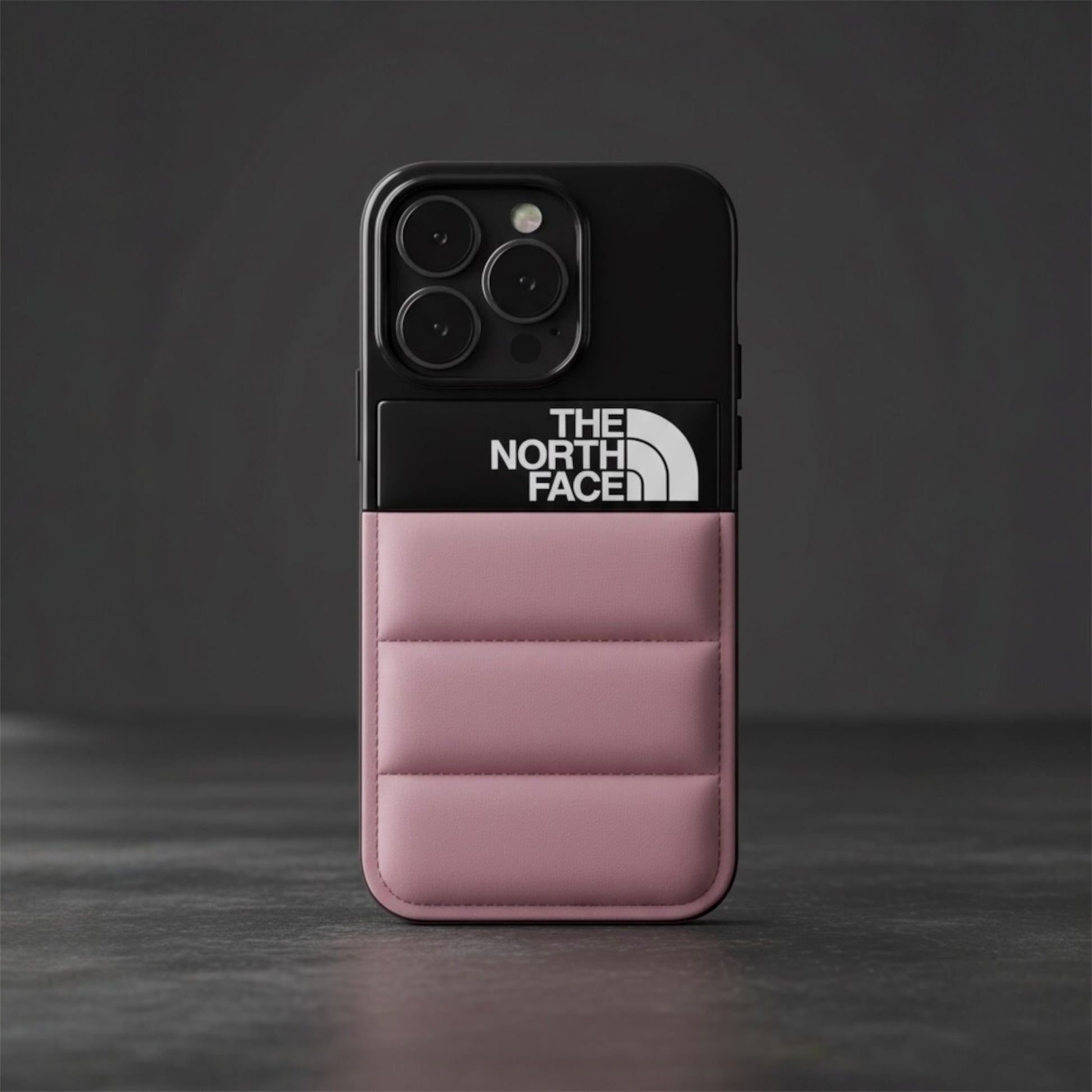 Pink padded The North Face phone case with black top, three camera lenses on gray background