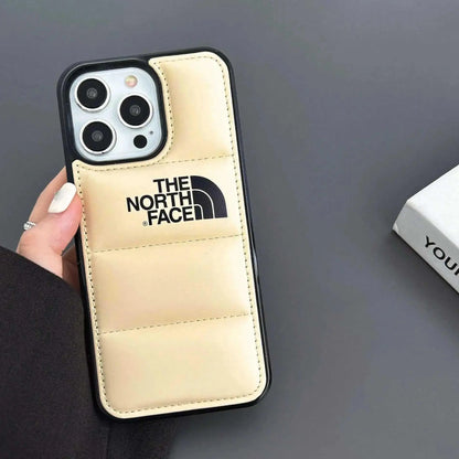 Beige padded The North Face iPhone case in hand on gray background