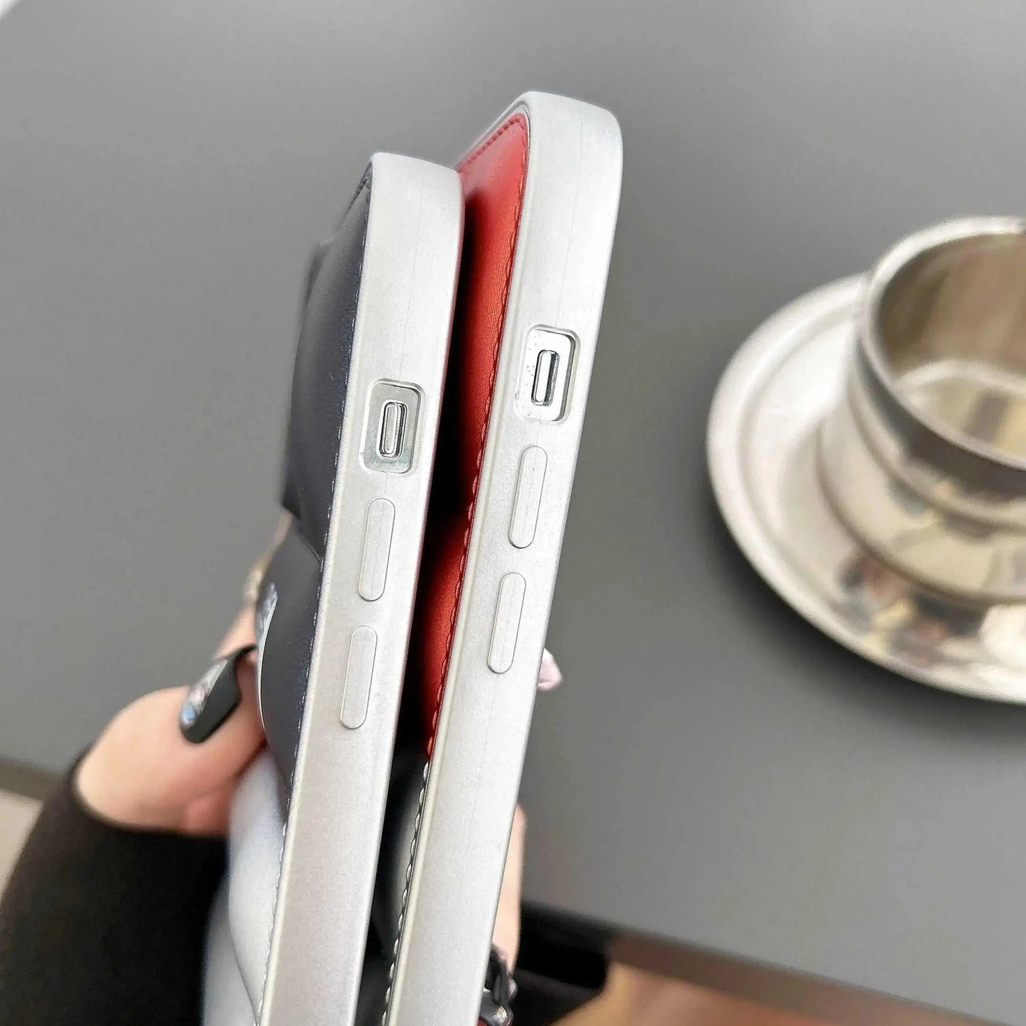 Close-up of two iPhones with black and red soft gomma cases, USB-C port visible